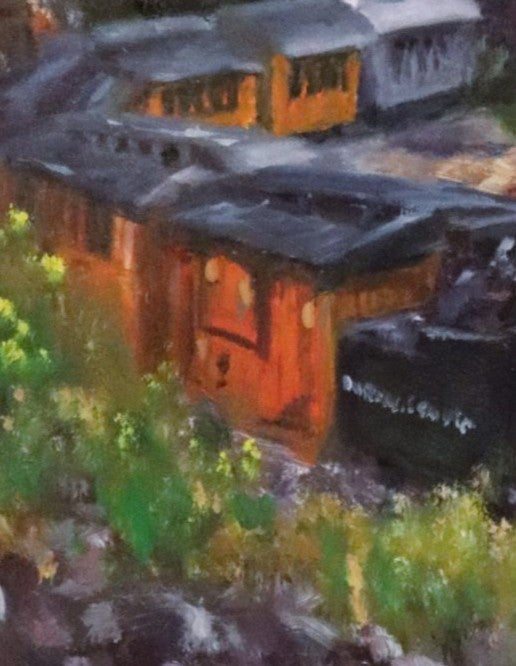 Close-up of a train with orange and black carriages on a grassy background